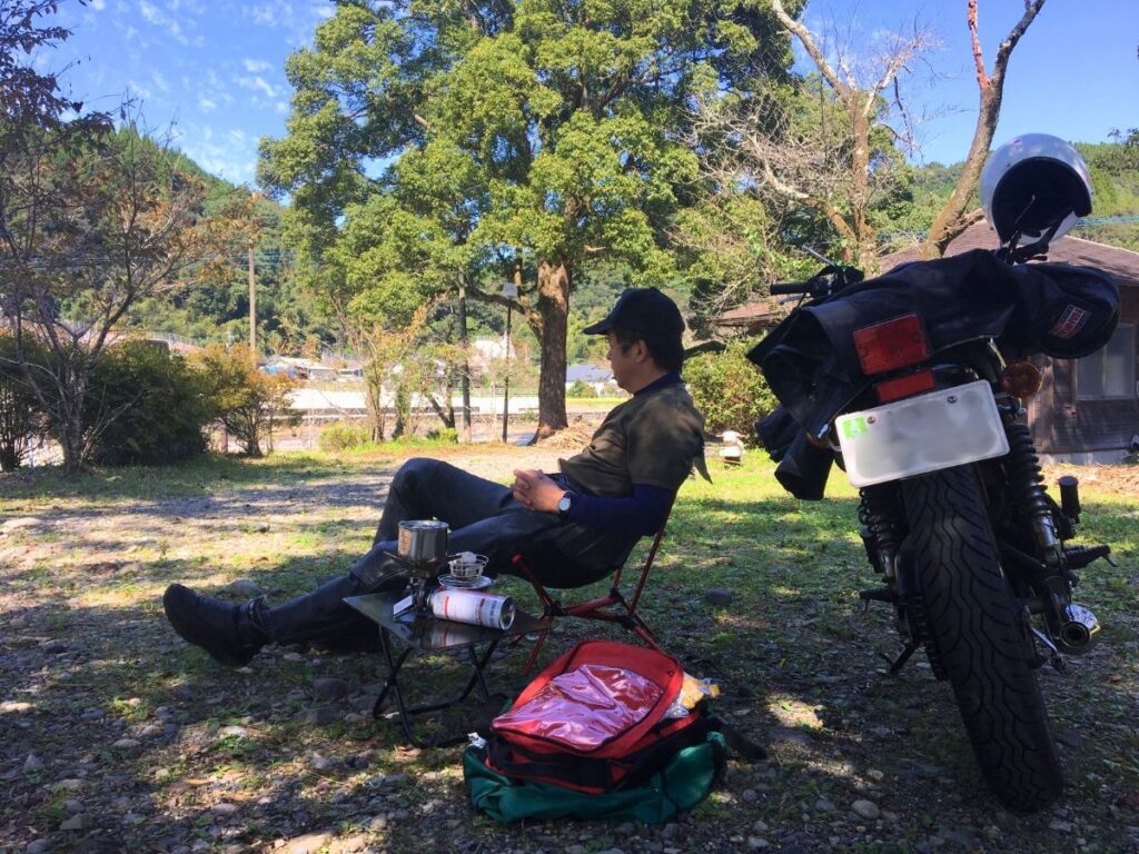 契約社員として働く筆者が、休日にソロツーリング先で、バイクの傍らで椅子に座り、アウトドアコーヒーを楽しんでいる写真